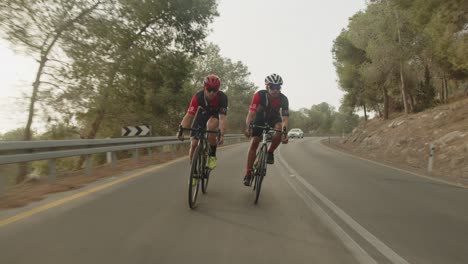 slow-motion-of-two-road-cycelist-professionals-riding-in-the-forest's-empty-road