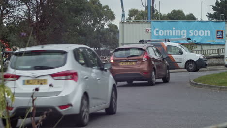 Tráfico-En-La-Carretera-En-Truro,-Cornwall-Con-Pancarta-Del-Supermercado-Aldi-Próximamente-En-Segundo-Plano