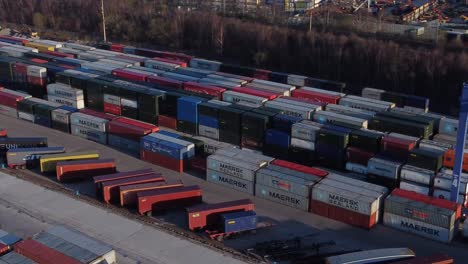 Shipping-container-crane-lift-unloading-heavy-cargo-export-crate-containers-in-shipyard-aerial-view-fast-panning-right-Birdseye