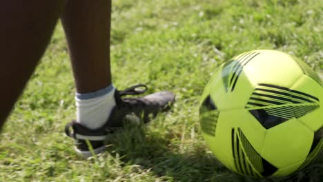 Seguir-De-Cerca-Al-Futbolista-De-Color-En-El-Campo-De-Fútbol---Centrarse-En-La-Pelota-Y-Las-Piernas,-Cámara-Lenta