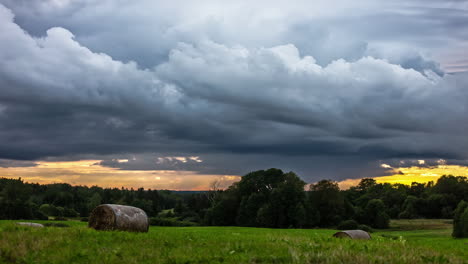 Dunkle-Wolken-Fliegen-über-Landwirtschaftliches-Feld-Während-Gelbem-Sonnenlicht-Und-Verstecken-Sich-Am-Horizont---Zeitrafferaufnahme