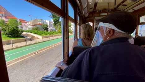 Los-Turistas-Visitan-La-Arquitectura-De-La-Calle-Lisboa-A-Través-De-Las-Ventanas-Abiertas-Del-Recorrido-En-Tranvía-Antiguo-Durante-El-Día-Cuando-Pasa-El-Automóvil