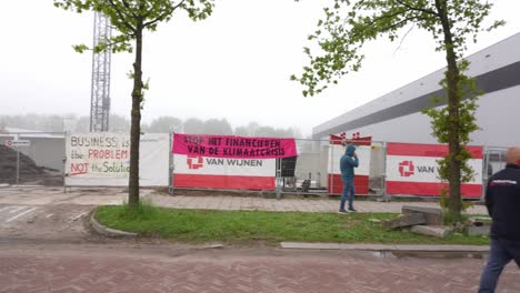 Establishing-shot-pan-reveal-group-of-people-protesting-against-climate-change-at-construction-site,-day