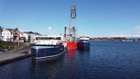 Portadores-De-Pescado-Ronja-Christopher-Y-Ronja-Strand-Junto-Con-Grúa-Barcaza-De-Elevación-Pesada-Uglen-En-El-Puerto-De-Leirvik-Noruega---Día-Soleado-Hermosa-Antena