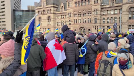 People-walking-around-a-Pro-Ukrainian-rally-against-war-invasion-from-Russia-at-Nathan-Phillips-Square-in-Toronto,-Ontario,-Canada