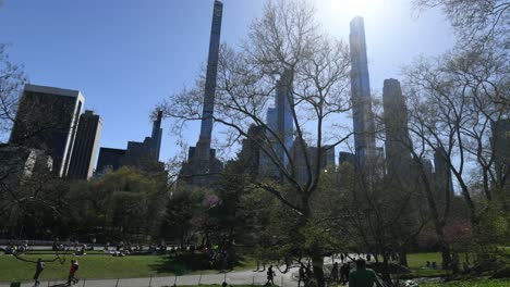 Multitudes-De-Personas-Disfrutando-De-Un-Hermoso-Día-Bajo-El-Sol-En-El-Parque-Central-Con-El-Horizonte-De-Manhattan-En-El-Fondo