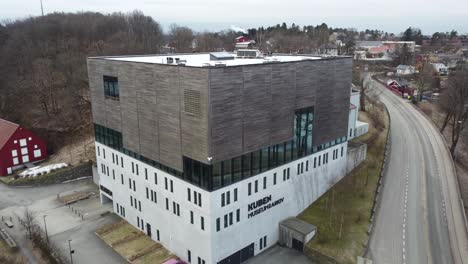 Museo-Y-Archivos-Kuben-En-Arendal-Noruega---Antena-De-Primer-Plano-Moviéndose-Hacia-Atrás-Y-Revelando-El-Exterior-Completo-Con-El-Fondo-De-La-Ciudad