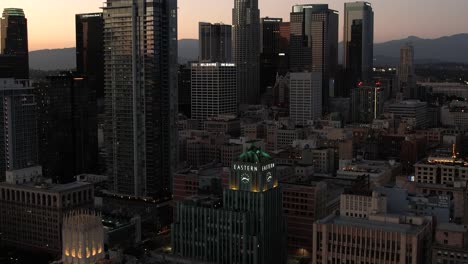 Establecimiento-De-Una-Vista-Aérea-Del-Centro-De-Los-ángeles-Al-Atardecer,-Edificio-Del-Este-De-Columbia-Con-Edificios-Rascacielos-Detrás