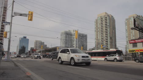 Timelapse-fast-motion-of-downtown-Yonge-Street-in-Toronto,-Cars-driving-people-crossing-streets-and-tall-buildings-in-background-in-a-city