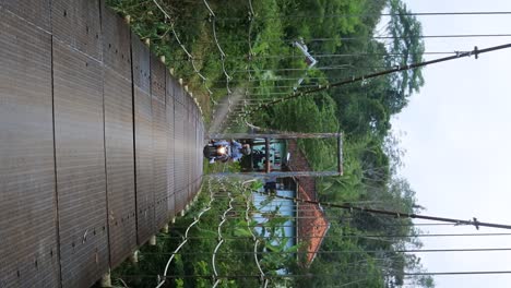 Puente-Colgante-Sobre-El-Río-Con-Cruce-De-Motocicletas-Por-La-Mañana-En-Sukabumi,-Java-Occidental,-Indonesia-El-4-De-Mayo-De-2022