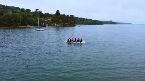 Orbit-Shot-Of-People-Rafting-In-Calm-Blue-Water-Surrounded-With-Green-Nature-Landscape,-California