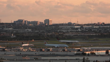 Paisaje-Del-Aeropuerto-Comercial-De-Toronto,-Aviones-En-Fila-Para-Despegar-Con-La-Ciudad-En-Segundo-Plano