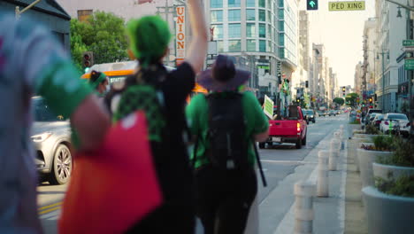 A-Crowd-of-Protesters-march-through-the-streets-of-Downtown,-led-by-a-truck