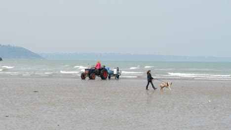 Chica-Paseando-Perro-Y-Gente-En-Tractor,-Martin-Beach,-Saint-Brieuc-Slomo