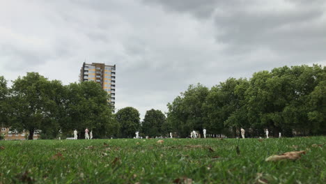 UK-August-2018---A-member-of-the-public-walks-past-as-two-teams-play-a-game-of-cricket