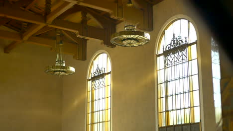 Inclinándose-Hacia-Abajo-Desde-Los-Candelabros-De-Techo-Ornamentados-Y-Las-Ventanas-Doradas-En-Los-Pasillos-Vacíos-De-Union-Station-En-Los-ángeles,-California