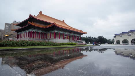 Slow-motion-shot-of-puddle-reflection-from-Performing-Arts-Library-of-National-Theater-and-Concert-Hall-at-Liberty-Square-in-Taipei,-Taiwan---slow-tilt