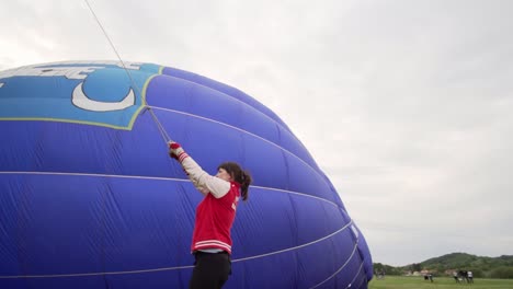 Schwenken-Sie-Um-Eine-Frau-Herum,-Während-Sie-Darum-Kämpft,-Den-Gefüllten-Ballon-An-Ort-Und-Stelle-Zu-Halten