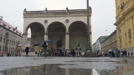 Weitwinkel:-Mehrere-Touristengruppen-Laufen-Bei-Regen-Um-Den-Odeonsplatz