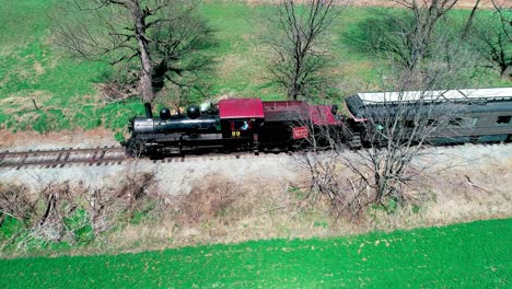 Steam-Train-Puffing-along-Amish-FarmLand-on-a-Sunny-Summer-Day-as-seen-by-a-Drone