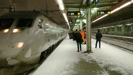 Es-Schneit-Und-Der-Sandinavia-Hochgeschwindigkeitszug-Kommt-An,-Während-Die-Leute-Am-Bahnsteig-Warten