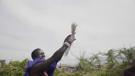 Massai-Mann-Versucht,-Feuer-Zu-Entfachen,-Indem-Er-Stroh-In-Den-Wind-Wirft,-Serengeti-Nationalpark,-Tansania