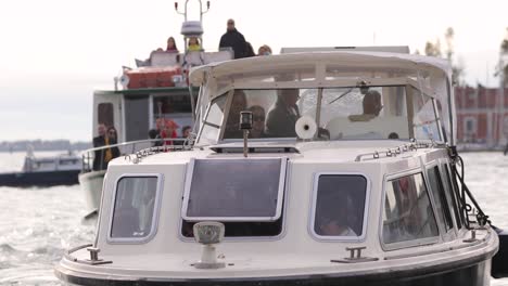 Close-shot-follows-two-touristic-cruise-boat-approaching-shore-with-happy-faces-of-People-enjoyIng-Venice-grand-canal-tour