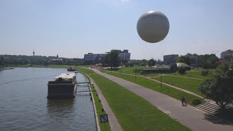 Río-Vistula-Con-Foro-De-Hotel-Y-Globo-Aerostático-En-El-Fondo,-Cracovia,-Polonia