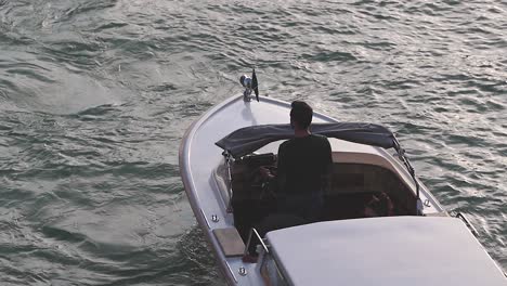 man-drive-luxury-motorboat-on-Venice-canals-reflecting-sunlight-during-winter