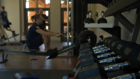 Dumbbells-in-a-fire-station-gym-with-fire-fighters-exercising-in-the-background