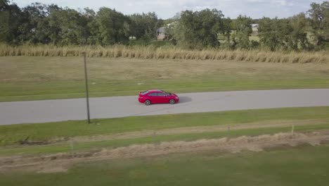 Aerial-View-of-Red-Sports-Car-From-Side-Driving-Through-Empty-Country-Road-at-Sunset