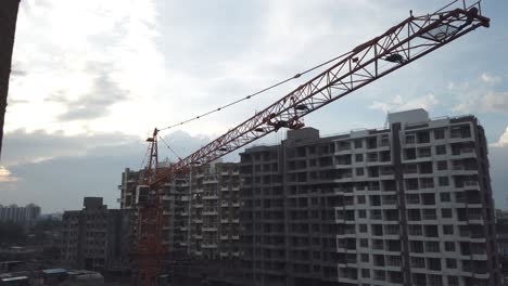 Ein-Kran-Schwenkte-An-Einem-Bewölkten-Abend-Mit-Wohnanlagen-Und-Verkehr-Auf-Der-Straße-über-Eine-Baustelle