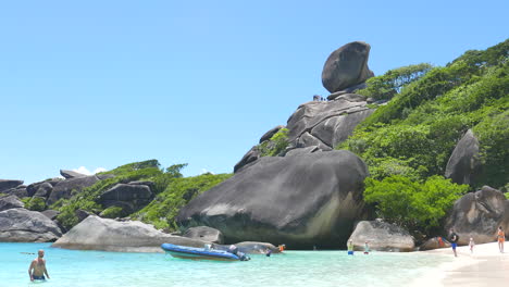 Phuket,-Tailandia---Vista-Aproximada-De-Las-Rocas-Gigantes-Cubiertas-De-Vegetación-En-La-Playa-De-Arena-Blanca-En-El-Parque-Nacional-De-La-Isla-Similar-En-Tailandia-Con-Turistas-Y-Un-Barco