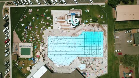 Tiro-De-Dron-Bajando-Directamente-Sobre-Una-Piscina-Pública-Al-Aire-Libre