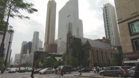 Street-corner-view,-downtown,-city-of-Chicago,-United-States,-Usa,-people-crossing,-traffic,-cars-passing,-tourists,-buildings,-skyscrapers,-cityscape,-smooth-zoom-in