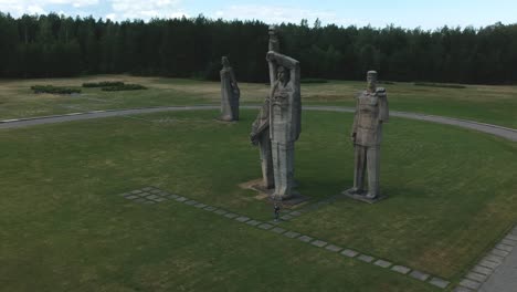 Aerial-shot-of-a-woman-walking-beside-a-very-huge-statues