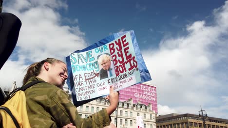 Eine-Junge-Schottische-Demonstrantin-Hält-Ihr-Selbstgemachtes-Schild-In-Der-Hand-Und-Betrachtet-Es