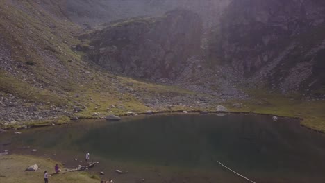 Aerial-view-of-a-large-group-of-people-relax-and-play-at-a-Lake-in-the-Rodnei-Mountains,-Romania