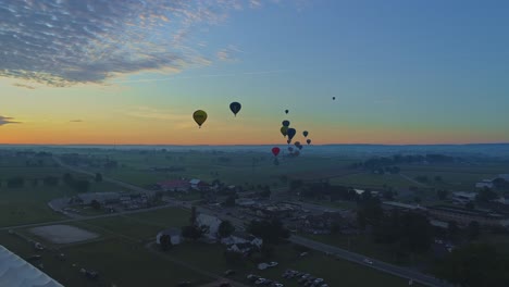 Luftaufnahme-Eines-Morgendlichen-Starts-Von-Heißluftballons-Bei-Einem-Ballonfestival-Vom-Befüllen-Bis-Zum-Abheben,-Wie-Von-Einer-Drohne-Gesehen