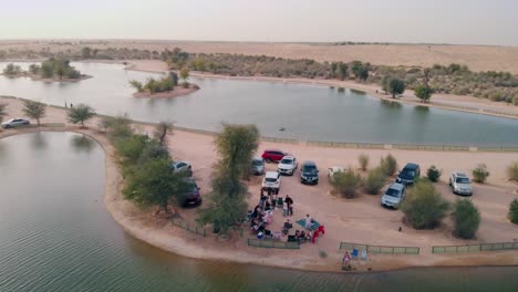 Aerial-view-from-drone-of-friends-having-a-picnic-near-Al-Qudra-lakes-in-Dubai-desert,-United-Arab-Emirates