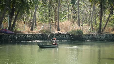 Wide-shot-of-native-indian-man-floating-in-wooden-canoe-boat-on-river-during-sunlight