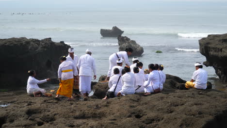 Balinese-locals-placing-their-daily-offering-for-the-Hindu-Gods-Brahma,-Vishnu-and-Shiva
