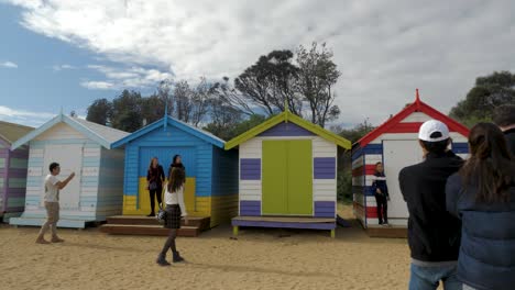 Tourists-walking-and-taking-photo-at-Brighton-Bathing-Boxes,-Melbourne,-Australia