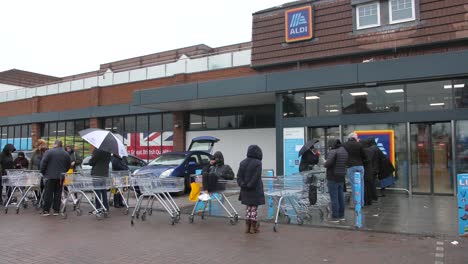 Die-Menschen-Stehen-Vor-Der-Supermarktkette-Aldi-An,-Bevor-Sie-Morgens-Geöffnet-Ist,-Um-Während-Der-Koronaviruskrise-Und-In-Vorbereitung-Auf-Die-Quarantäne-In-Großbritannien-Einzukaufen-Und-Sich-Mit-Lebensmitteln-Einzudecken