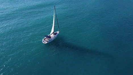 Toma-Aérea-Para-Velero-Con-Vail-En-El-Mar-Con-Reflejos-De-Luz-Solar