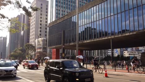 Decenas-De-Ciclistas-Y-Autos-Cruzando-La-Avenida-Paulista,-Frente-Al-Museo-De-Arte-De-Sao-Paulo,-Masp