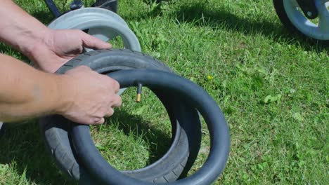 Vista-Cercana-De-Un-Hombre-Reparando-Un-Neumático-De-Rueda-De-Cochecito