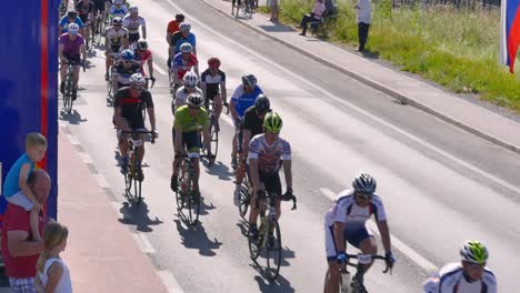 Eine-Große-Gruppe-Von-Radrennteilnehmern,-Die-An-Leuten-Vorbeikommen,-Die-Ihnen-Zuschauen-Und-Ihnen-Zuwinken