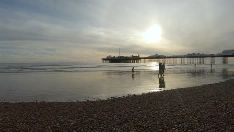 Puesta-De-Sol-Dorada-Sobre-La-Playa-De-Brighton-En-El-Reino-Unido-Con-Gente-Caminando-Y-Disfrutando-Del-Agua