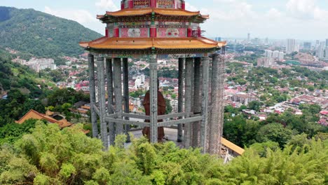 Back-view-of-Kuan-Yin-Goddess-of-Mercy-statue-monument-with-repair-scaffolding-in-Kek-Lok-Si-Buddhist-temple,-Aerial-drone-closing-in-orbit-reveal-shot